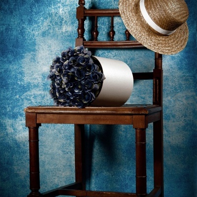 Cadeira de madeira com chapéu de palha e vaso de flores azuis