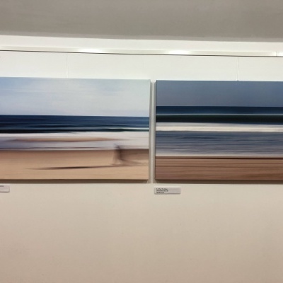 Duas pinturas abstratas de paisagens costeiras com faixas horizontais em tons azul, branco, bege e castanho