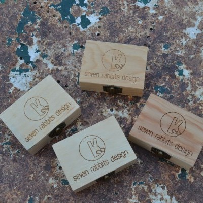 Quatro caixas de madeira com gravação 'seven rabbits design' sobre superfície enferrujada