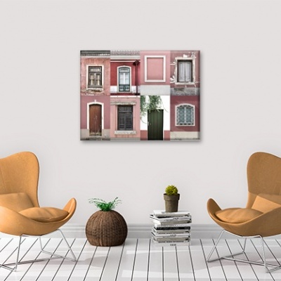 Sala com duas cadeiras castanhas, vaso de fibras, mesa de livros e quadro de fachadas rosas na parede