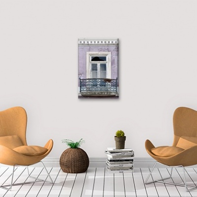 Duas cadeiras caramelo, objetos decorativos e quadro de varanda numa sala branca