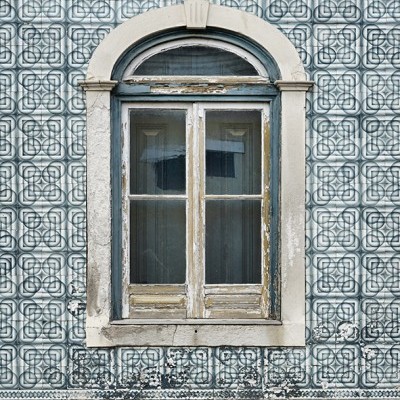 Janela antiga em parede com azulejos azuis e brancos e moldura de pedra