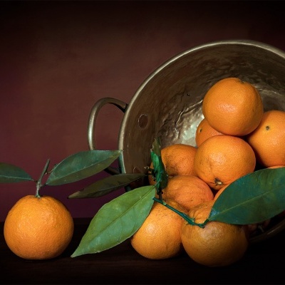 Cesto metálico com tangerinas laranjas e folhas verdes