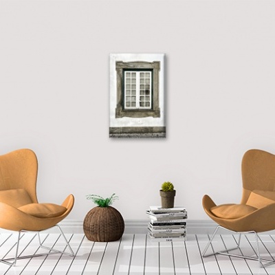 Sala com duas cadeiras castanhas claras, plantas em vasos, pilha de livros e moldura de janela na parede branca