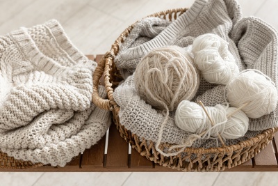 Cesto com tecidos de malha e bolas de lã em tons neutros