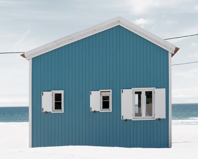 Casa de praia azul com janelas brancas e mar ao fundo