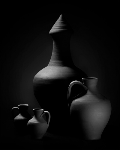 Quatro jarros em cerâmica preta sobre fundo escuro