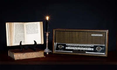 Rádio vintage Telefunken com livros antigos e castiçal com vela