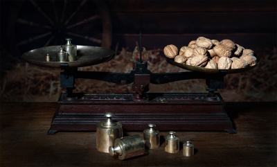 Balança antiga com nozes e pesos metálicos sobre mesa de madeira