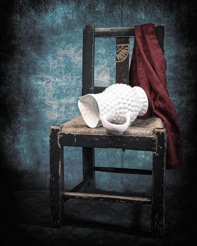 Cadeira antiga de madeira preta com jarro branco e tecido vermelho