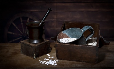 Almofariz, caixa de madeira e concha metálica com feijões brancos sobre mesa de madeira