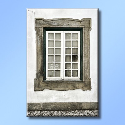 Janela branca com moldura em pedra cinzenta e vidro partido numa parede branca