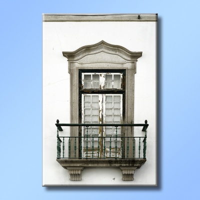 Janela decorativa em pedra com varanda em ferro preto numa parede branca