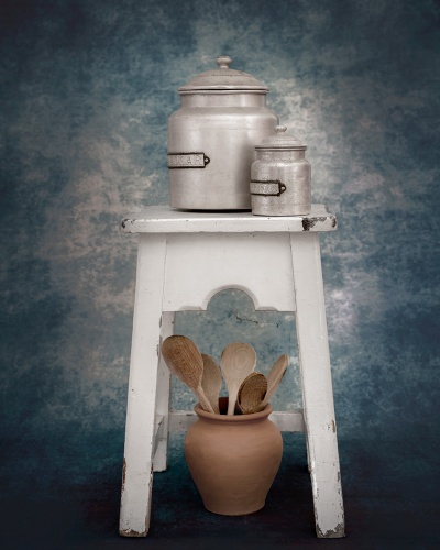Dois recipientes metálicos sobre banquinho branco com vaso de cerâmica e colheres de pau