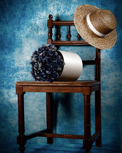 Cadeira de madeira com chapéu de palha e vaso de flores azuis