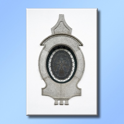 Elemento arquitetônico oval em pedra cinzenta com decoração preta numa parede branca