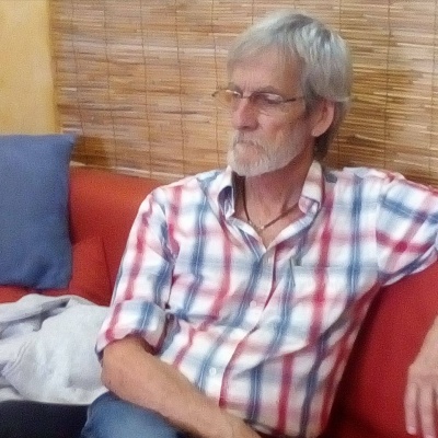 Homem sentado no sofá vermelho com camisa xadrez