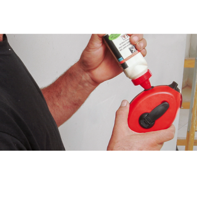 Pessoa a usar um aplicador de cola com caixa vermelha e botão preto