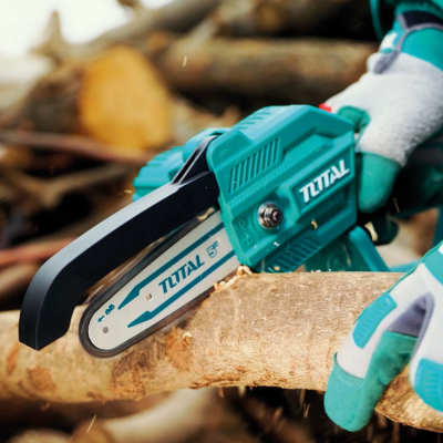 Motosserra elétrica azul a cortar um tronco de madeira com luvas de proteção