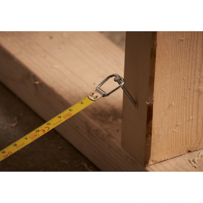 Fita métrica amarela presa em prego numa peça de madeira clara