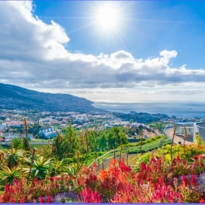 Vista panorâmica de cidade costeira com jardim florido e mar ao fundo
