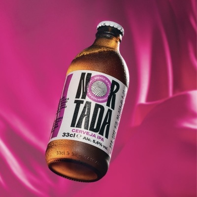 Garrafa de cerveja NORTADA IPA com rótulo branco e rosa em fundo rosa com tecido
