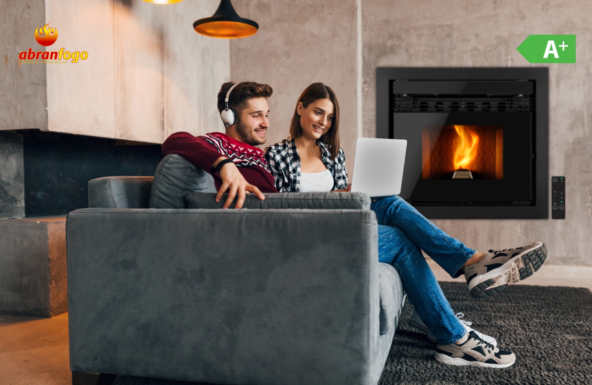 ABF NEO Casal sentado em sofá cinza perto de salamandra a lenha embutida com fogo visível