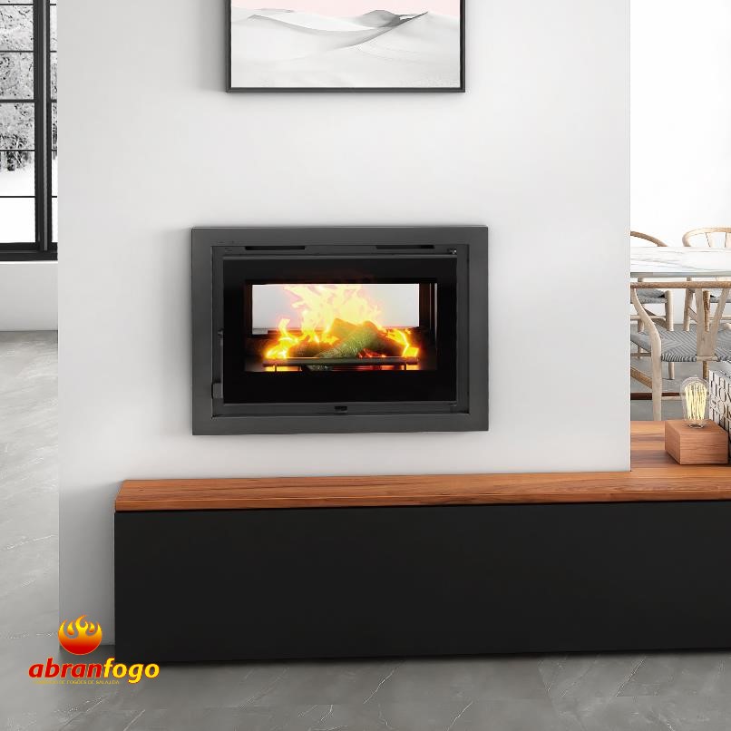 ABF IT-172 K Lareira embutida preta com fogo aceso numa parede branca com banco preto e madeira.