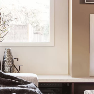 Lareira embutida preta com painel metálico perfurado num ambiente interior com cadeira e janela