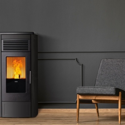 Lareira a pellet preta com fogo, cadeira cinzenta e parede cinzenta