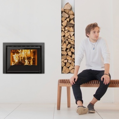 Lareira embutida com lenha e homem sentado num banco de madeira