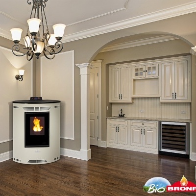 Lareira a pellets cinza oval numa sala com pavimento de madeira e cozinha branca visível