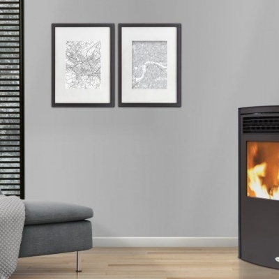 Lareira a pellets num canto de sala com sofá e manta cinzentos, paredes cinzentas, quadro e persiana preta