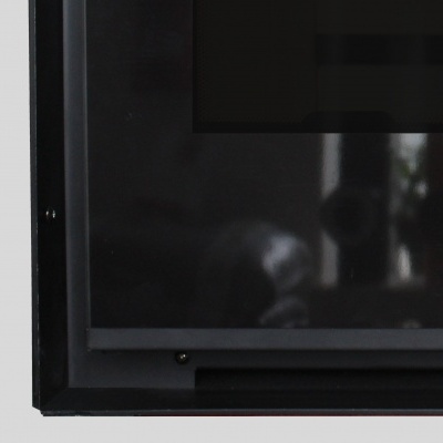 Monitor preto com moldura fosca e reflexo da sala.