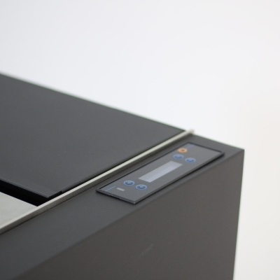 Caixa retangular preta com painel digital e botões num canto