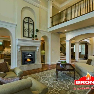 Sala de estar com lareira acesa, móveis bege, tapete cinzento e logo BRONPI.