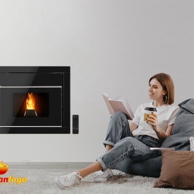 Salamandra embutida preta com fogo, mulher sentada no chão a ler e beber, sofá e tapete cinzento