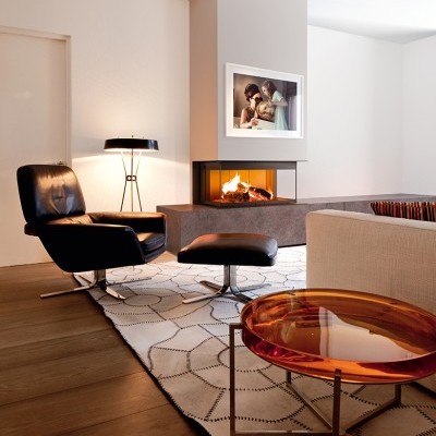 Sala de estar moderna com poltrona preta, tapete branco e mesa de centro âmbar