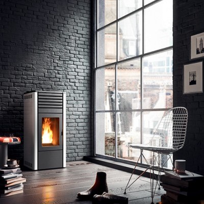 Sala moderna com lareira acesa e cadeira aramada junto a uma grande janela.