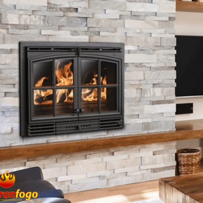 Lareira embutida de ferro preto com vidro numa parede de pedra clara