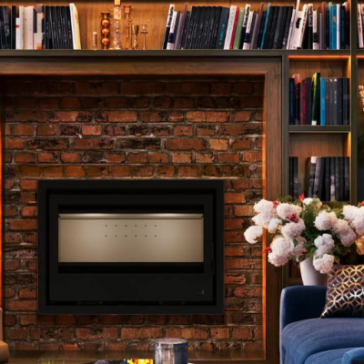 Lareira embutida Aveiro C795 numa parede de tijolos com estante de madeira e livros, decoração com flores e móveis coloridos