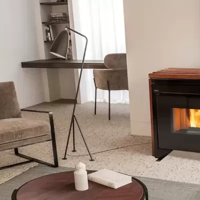 Sala de estar com lareira a lenha instalada na parede branca e cadeira castanha com estrutura metálica preta