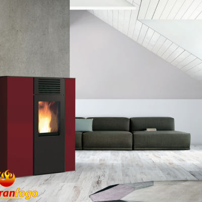 Salamandra bordô e preta com chama, numa sala com sofá cinza e chão de madeira clara