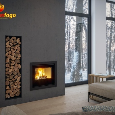 Sala de estar moderna com lareira embutida e armazenamento vertical de madeira ao lado, vista para floresta nevada através de janelas grandes.