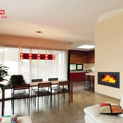 Sala de jantar com lareira embutida, mesa de madeira, cadeiras pretas, sofá branco e candeeiro vermelho suspenso