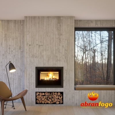 Lareira moderna embutida com lenha, cadeira castanha, candeeiro preto e janela com vista para floresta.