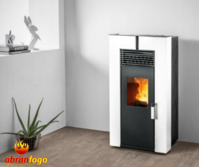 Lareira a pellets branca com porta preta e fogo visível, junto a planta e prateleira em ambiente minimalista