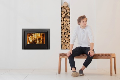 Lareira embutida com lenha e homem sentado num banco de madeira