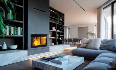 Sala de estar com lareira, estantes pretas, sofá cinzento e mesa de centro em mármore.