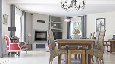 Sala de jantar e estar com mesa de madeira e cadeiras rattan